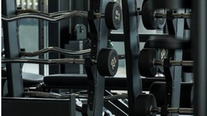 Ein Fitnessraum mit Krafttrainingsgeräten, darunter ein Squat-Rack und Kurzhanteln.