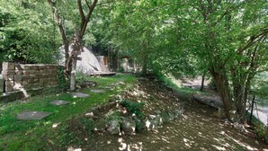 A stone pathway leading through a wooded area with a rustic building in the background. - Villa 'theMAP' with Balcony and Wi-Fi (Lenzkirch)
