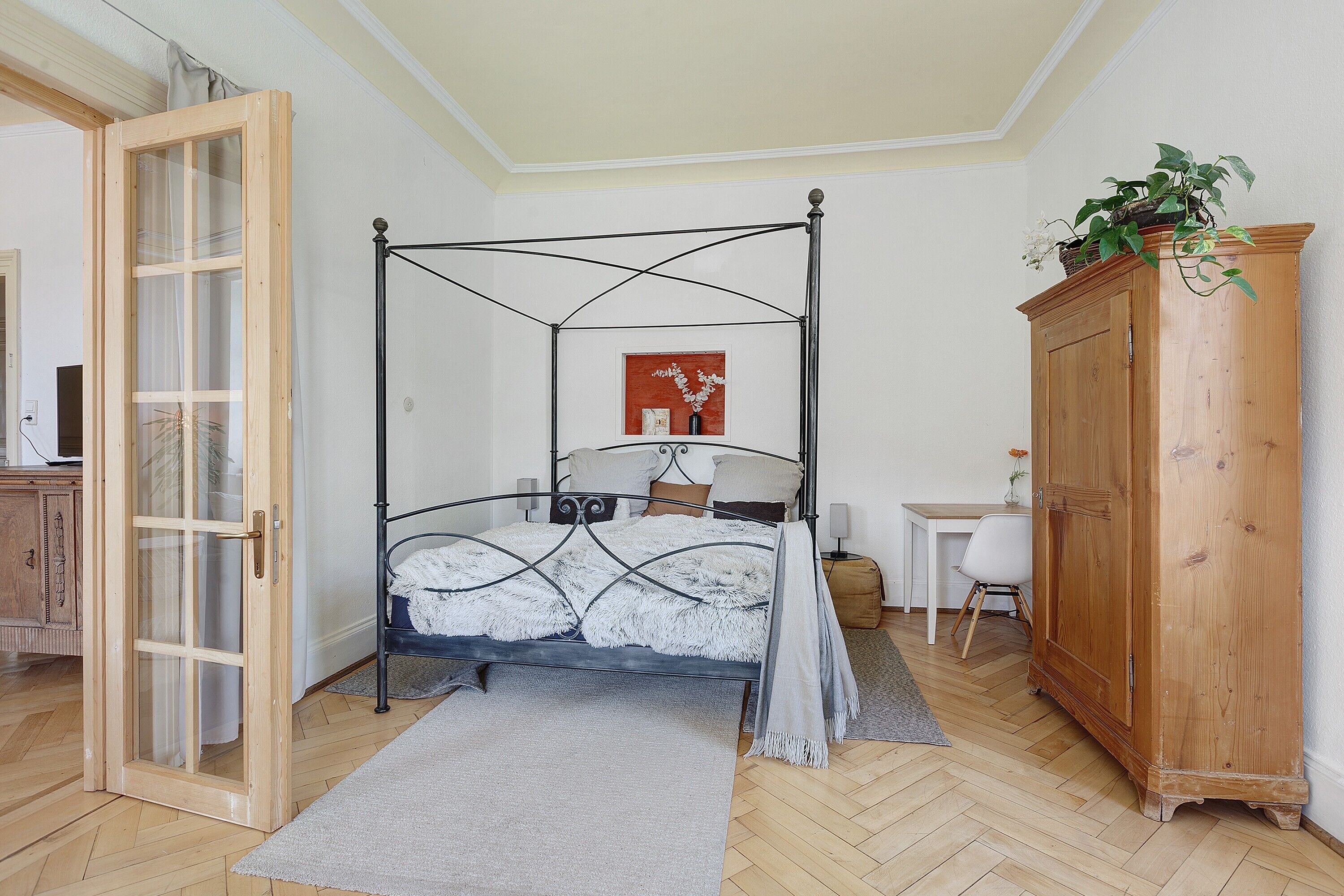 Una habitación con cama con dosel, un armario de madera, un escritorio y una silla.
