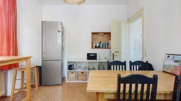 Eine kleine Küche mit Kühlschrank, Mikrowelle und Holzregalen.