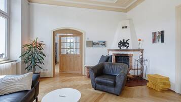 A living room with a fireplace, a sofa, a coffee table, and a potted plant.