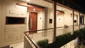A modern building with a balcony, a wooden door, and a stone pillar. - Cozzy Saren Guesthouse (Kerobokan)
