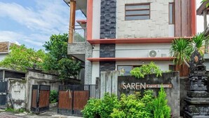A modern guest house with a stone facade, a visible entrance gate, and a sign reading 'Saren Guest House.' - Cozzy Saren Guesthouse (Kerobokan)