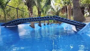 Una piscina con uno scivolo blu e palme sullo sfondo.