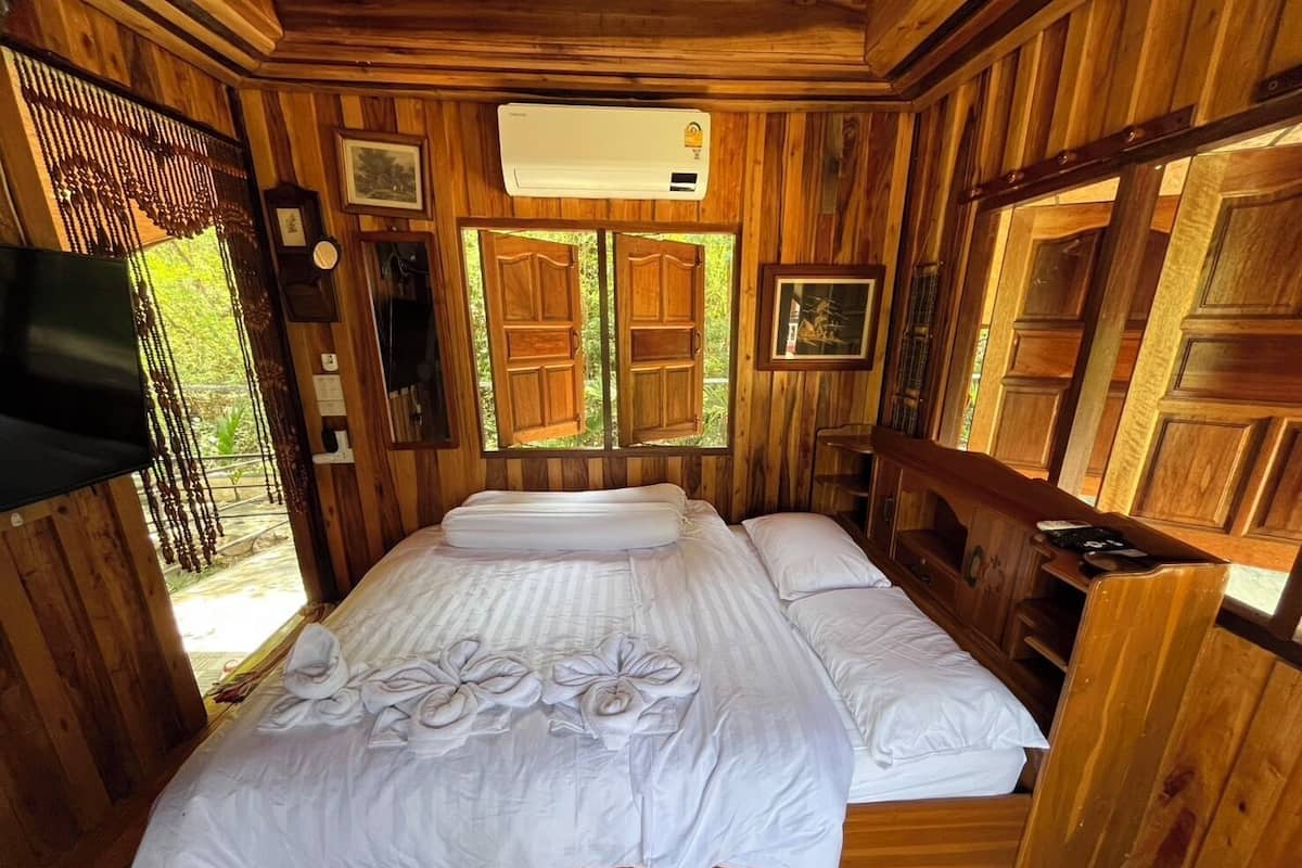 Una habitación de madera con una cama, un televisor y un ventanal.