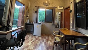Una stanza compatta con soffitto in legno, angolo cottura, tavolo con sedie e una grande finestra.