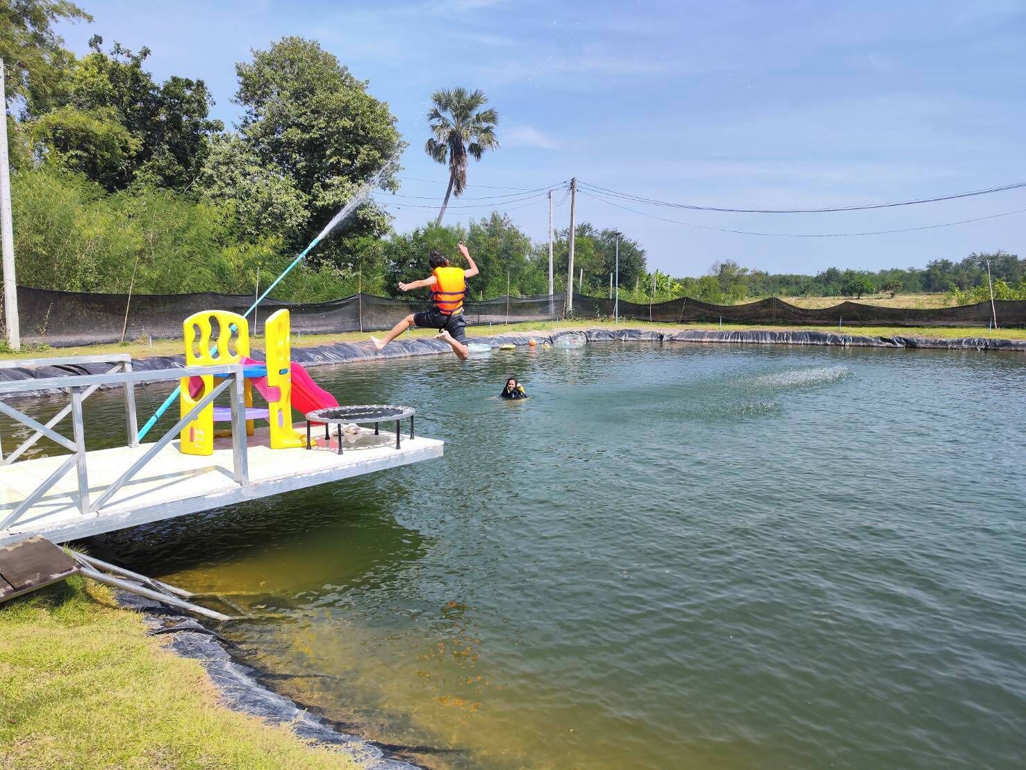 Un cuerpo de agua con un muelle, un trampolín y un tobogán.