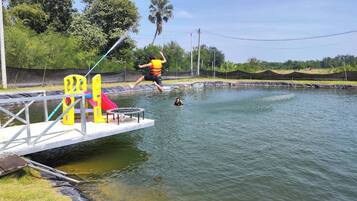 Un cuerpo de agua con un muelle, un trampolín y un tobogán.
