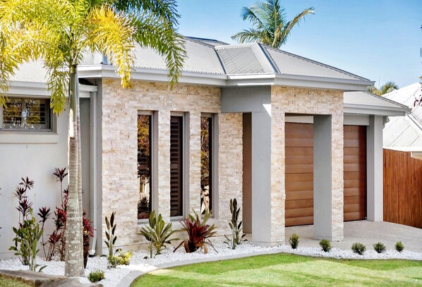 A modern house with a brick facade, large windows, and a well-maintained lawn. - Palm Breeze Luxury House With A Private Pool (Coomera)