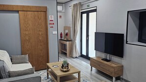 En moderne stue med sofa, sofabord, fjernsyn og et træskab.