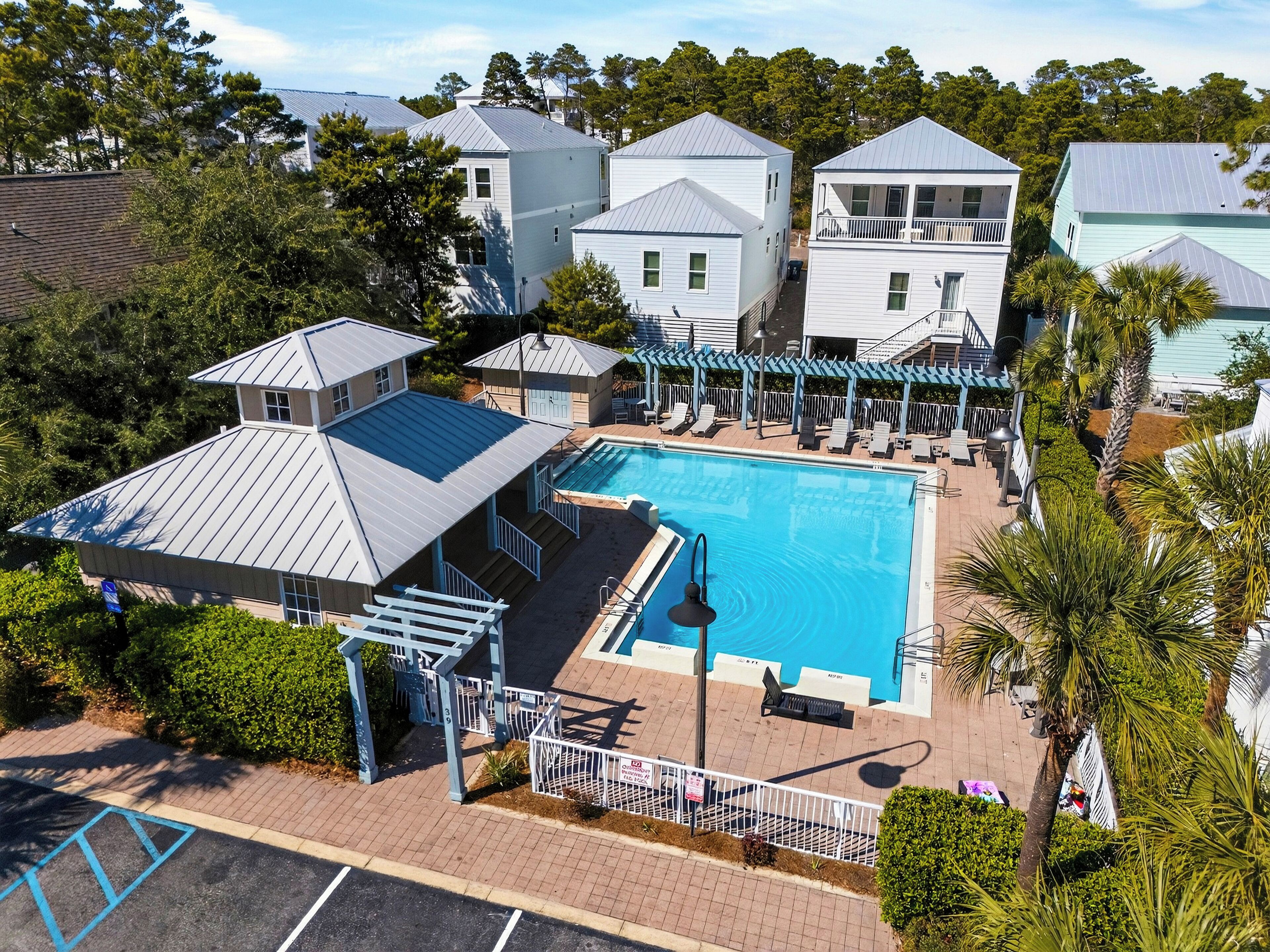 A pool area with a clear view of the pool, lounge chairs, and a covered seating area.