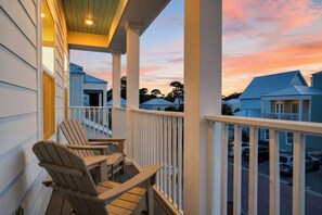 A balcony with chairs, a railing, and a view of neighboring houses during sunset. - Pool + Outdoor Lounge + Golf Cart | Minutes to the Beach | Southern Dream on 30A (Santa Rosa Beach)