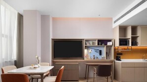 A modern hotel room with a dining area, a kitchen, and a large flat-screen TV. - Home2 Suites By Hilton Beijing Shunyi  (Shunyi)
