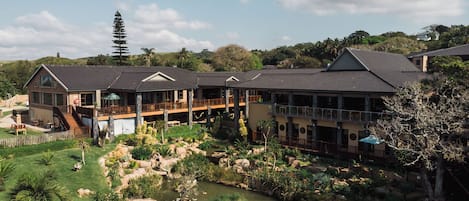 Ein Resort mit einem großen Gebäude, Sitzgelegenheiten im Freien und einem Teich.