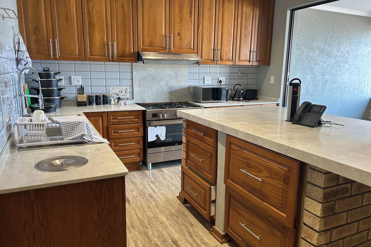 A kitchen with wooden cabinets, a stove, a microwave, and a phone on the counter.