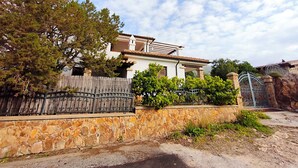 Una casa con un muro de piedra, una valla de madera y un portón de metal.