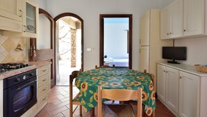 Cocina compacta con comedor, televisor y vista a través de una puerta abierta.
