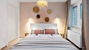 Quarto com cama, mesas de cabeceira, luminária pendente e parede decorada.
