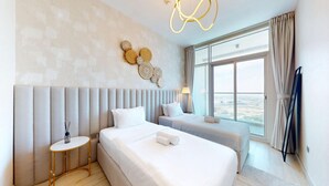 A hotel room with a large bed, a smaller bed, a bedside table, a lamp, and a view of the city through large windows. - Stunning 2 Bed l Sea and City Views l Dubai Marina (Dubai Marina)