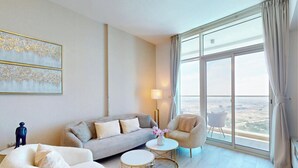 A modern living room with a sofa, armchair, and a view through large windows. - Stunning 2 Bed l Sea and City Views l Dubai Marina (Dubai Marina)