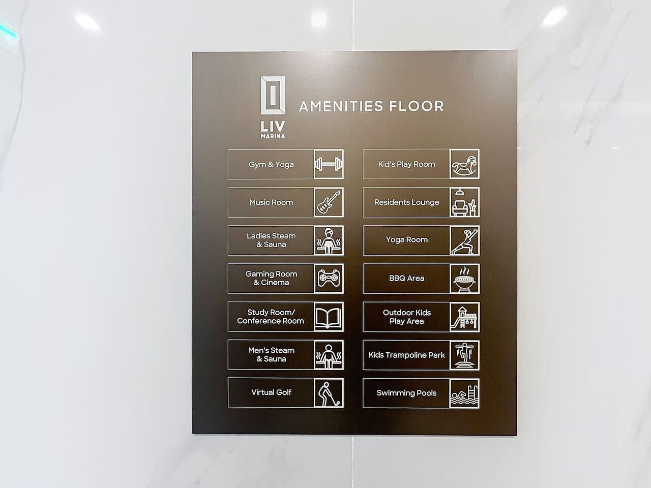 A sign listing amenities on the LIV Marina's amenities floor, including a gym, yoga room, and swimming pools.