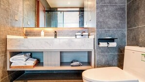 A modern bathroom with a marble vanity, a toilet, and a built-in shelf with towels. - spiderSix (Meishan)