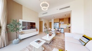 A modern living room with a TV, sofa, coffee table, and dining area. - Exquisite 2 Bed l City View near Dubai Hills Mall (Dubai Hills)