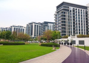 A modern building complex with multiple high-rise structures, a well-maintained lawn, and a curved pathway. - Exquisite 2 Bed l City View near Dubai Hills Mall (Dubai Hills)