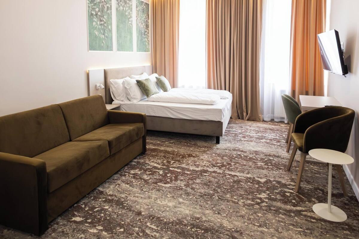Une chambre d’hôtel avec un lit, un canapé, un bureau et une télévision.