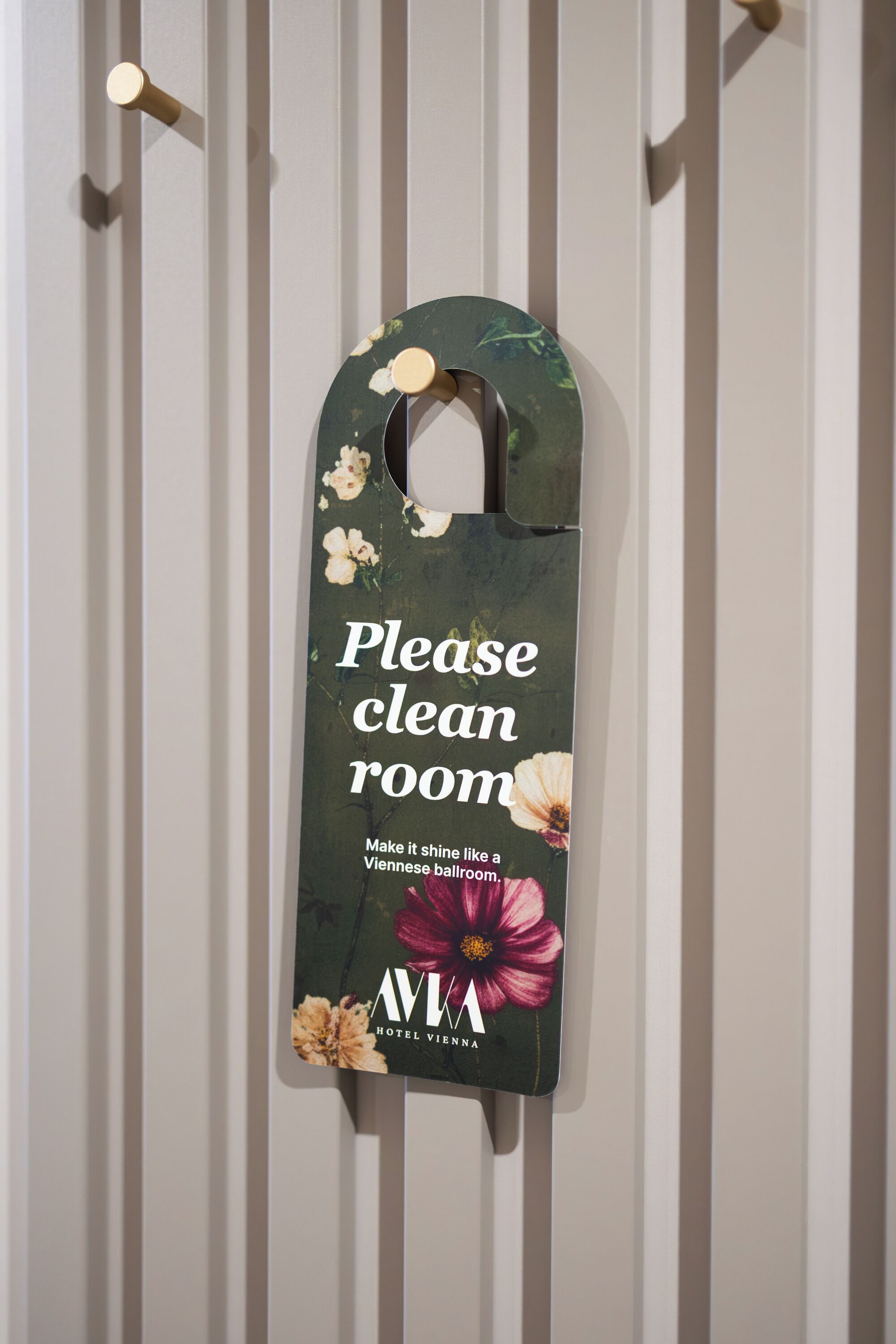 A wall-mounted sign with a floral design and text instructing to clean the room.