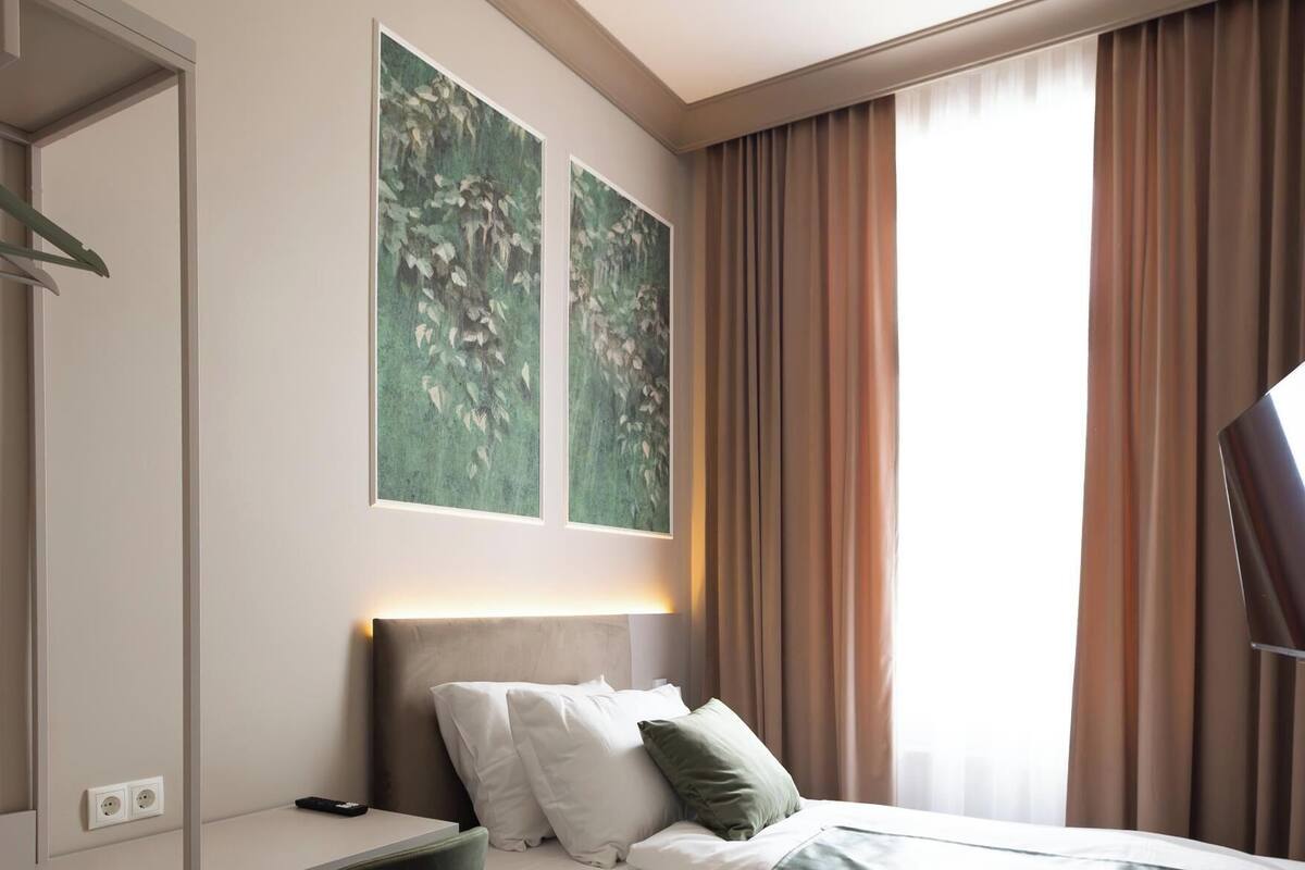 Une chambre d’hôtel comprenant un lit, un bureau, une chaise et deux tableaux accrochés au mur.
