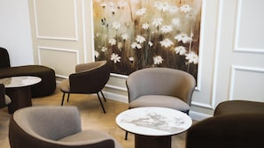 Een modern interieur met ronde tafels en grijs gestoffeerde stoelen, een bloemen behang en houten vloeren.