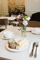 Un tavolo da pranzo con un piatto di cibo, una tazza di caffè, un vaso di fiori e posate.
