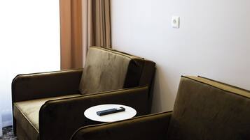 A room with two brown sofas, a small white table, and a window with curtains.