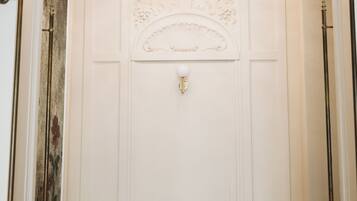 A hallway with a bench, a chandelier, and a door with a decorative panel.
