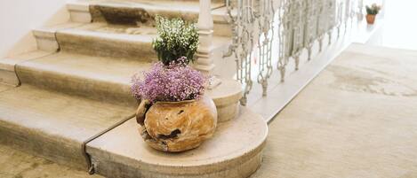 A staircase with a white railing and a potted plant with purple flowers on the landing.