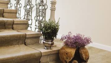 A staircase with ornate metal railings and a potted plant with purple flowers.