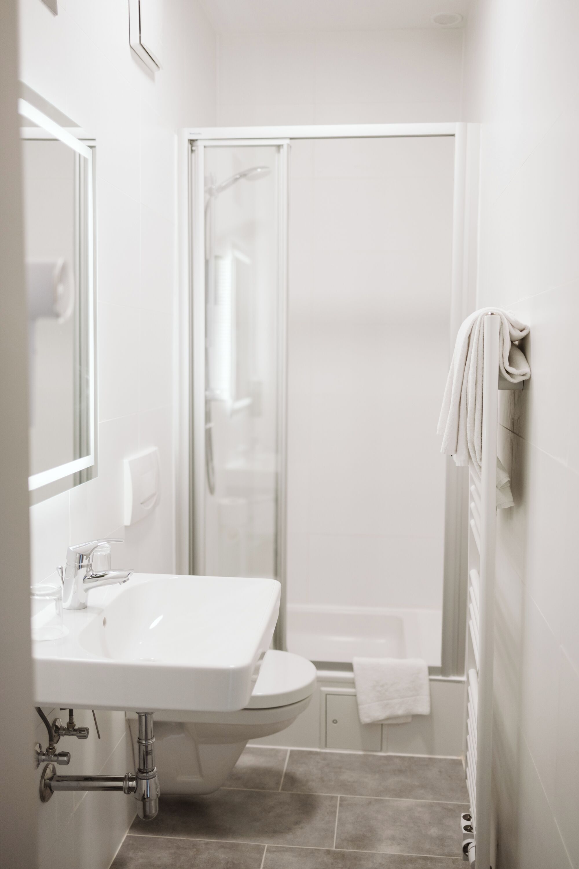 A modern bathroom with a white sink, toilet, and shower.