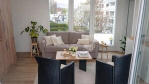 Un salon moderne avec un canapé, deux fauteuils, une table basse et une plante en pot.