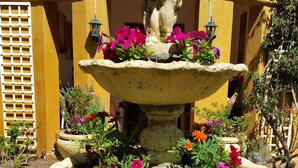 Ein mehrstufiger Steinbrunnen mit bunten Blumen in einem Innenhof.