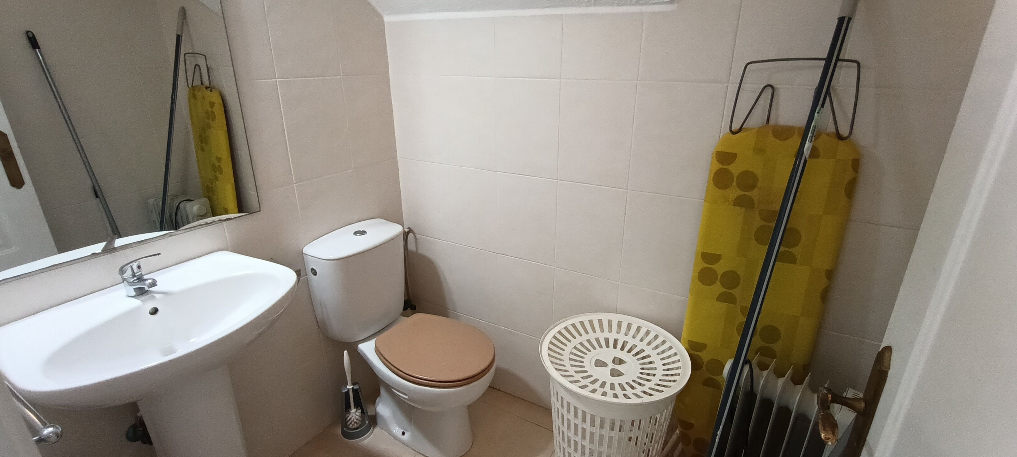 A bathroom with a toilet, sink, and a trash bin.