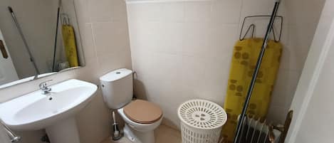 A bathroom with a toilet, sink, and a trash bin.