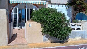 Een gebouwtoegang met een hekpoort, een klein terras en een bloempot.