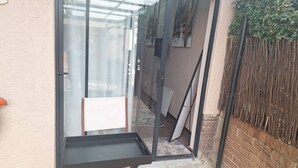Una puerta de cristal da a un patio con una pequeña mesa y una silla.