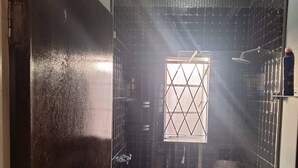 Un baño con ducha, inodoro y ventana con diseño de rombos.