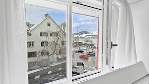 A piano with a view of a snowy landscape through a window. - Elegant Lake Zurich House with Stunning Views and Private Terrace (Stäfa)