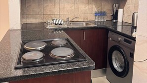 Cocina compacta con estufa, lavaplatos y lavadora.