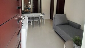 A modern interior with a dining area, sofa, and kitchen. - Manzil Anilao Unit 1 - Ground Floor 1st Room (Mabini)