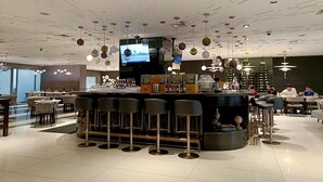 A modern bar area with a TV screen, bar stools, and a variety of bottles. - Lerfo Staycation!!!! (Mandaluyong City)