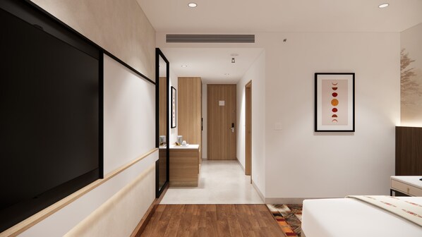 Hotellihuone, jossa on suuri sänky, työpöytä, peili ja seinällä kehystetty taulu.